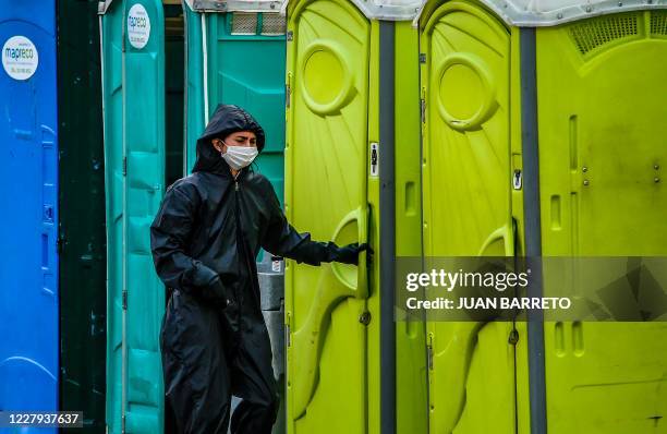 Woman wearing a protective suit uses a public toilet in Bogota on August 6 amid the COVID-19 pandemic. - More than 200,000 people have died from...