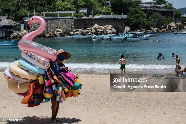 An inflatable vendor walks the beaches during a day as part of the new normal on August 6, 2020 in Acapulco, Mexico. Acapulco remains as one of the...