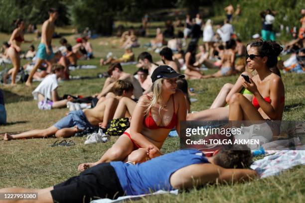 People sunbathe by Hampstead Heath ponds as the temperature soars in London on August 7, 2020.