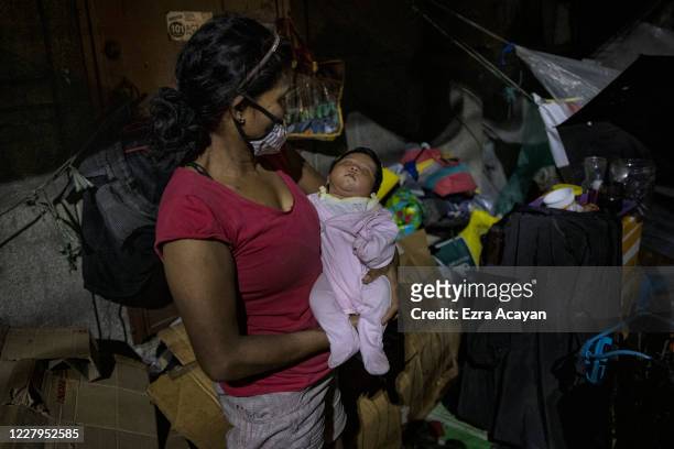 Laura Amaya carries her one-month-old granddaughter Angelica Nicole outside their makeshift home along a sidewalk on August 7, 2020 in Caloocan,...