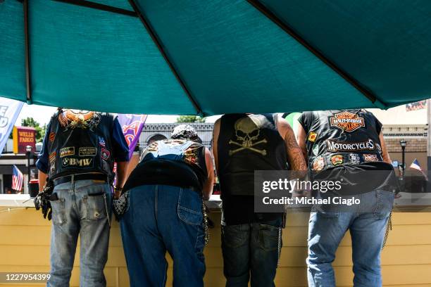 People watch from a balcony as motorcyclists drive down Main Street during the 80th Annual Sturgis Motorcycle Rally on August 7, 2020 in Sturgis,...