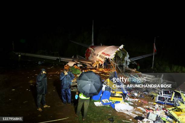 Security personnel stand in front of the wreckage from an Air India Express jet, which was carrying more than 190 passengers and crew from Dubai,...