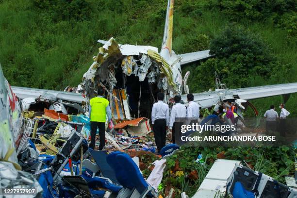 Officials inspect the wreckage of an Air India Express jet at Calicut International Airport in Karipur, Kerala, on August 8, 2020. - Fierce rain and...