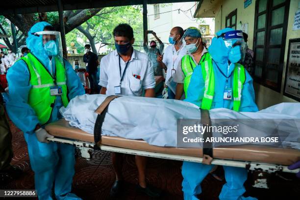 Medical staff wearing Personal Protective Equipment suits carry the body of a victim inside the medical college where Air India Express jet crash...