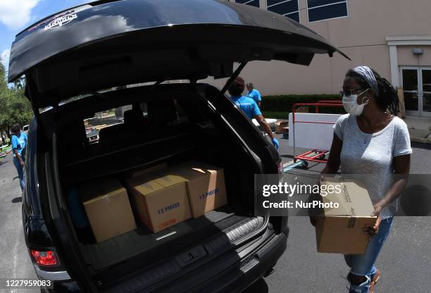 Volunteer distributes food from the Second Harvest Food Bank of Central Florida to the needy at Church in the Son on August 7, 2020 in Orlando,...