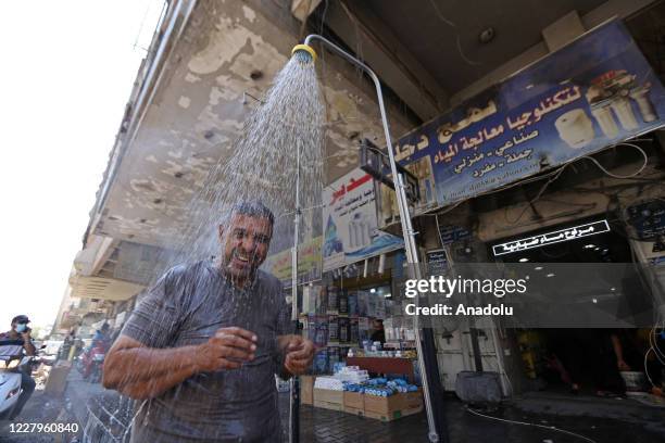 Man cools off under roadside shower as temperatures exceed 45Â°C in the capital city Baghdad, Iraq on August 08, 2020.