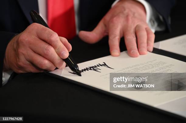 President Donald Trump signs executive orders extending coronavirus economic relief, during a news conference in Bedminster, New Jersey, on August 8,...