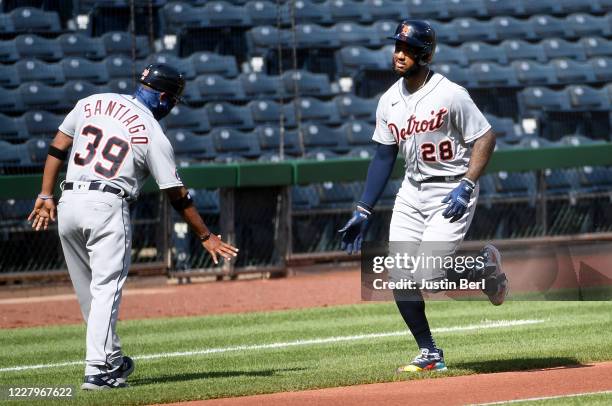 Niko Goodrum of the Detroit Tigers celebrates with third base coach Ramon Santiago as he rounds the bases after hitting a solo home run in the first...