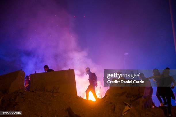 Protestors make their way past a fire lit by an Internal Security Forces tear gas canister during a protest near Martyrs Square on August 9, 2020 in...