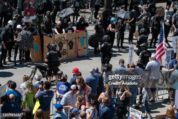 Protesters and counter protesters are separated by police during the Seattle Police Officers Guildâs rally to stop defunding of the Seattle Police...