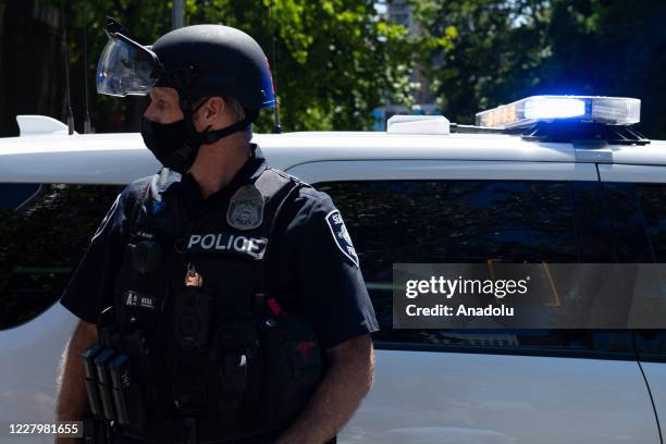 Police officer stands next to a police car during the Seattle Police Officers Guildâs rally to stop defunding of the Seattle Police Department on...