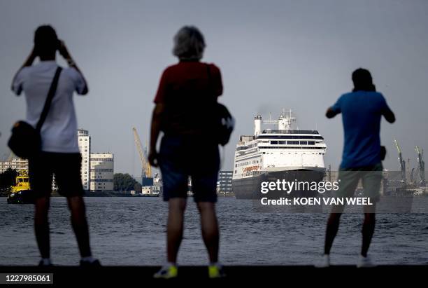People watch as cruise ship MS Rotterdam of the Holland America Line arrives at the Wilhelminakade pier in Rotterdam on August 10, 2020. The ship...