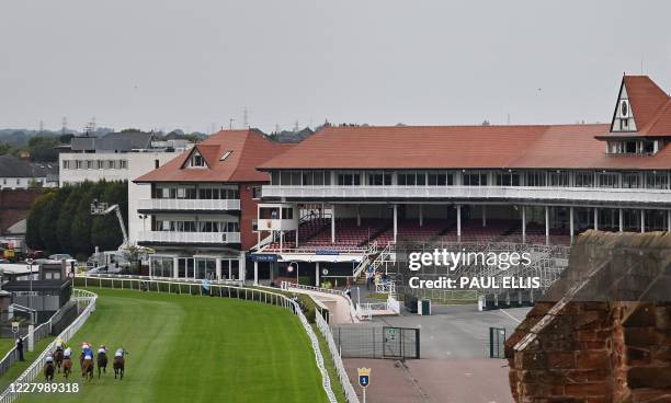 Jockeys ride their horses past the empty stands in the British Stallion Studs EBF Novice Stakes horse race at Chester Racecourse in Chester,...