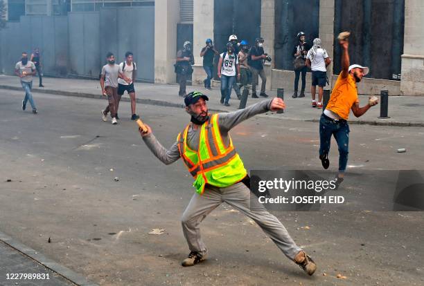 Lebanese security hurl stones at security forces amid clashes in the vicinity of the parliament in central Beirut on August 10 following the deadly...