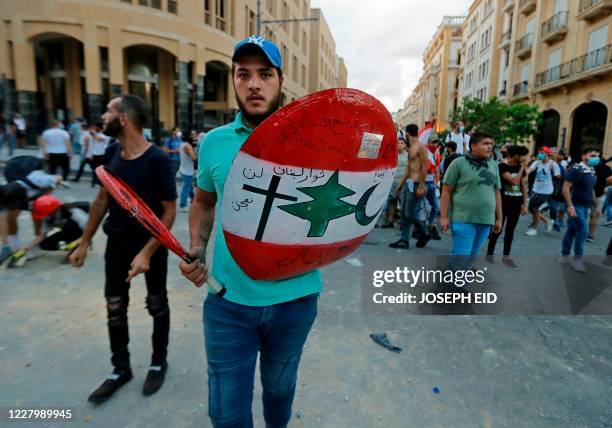 Lebanese protester holds a makeshift shield and a tennis racket amid clashes with security forces in the vicinity of the parliament in central...