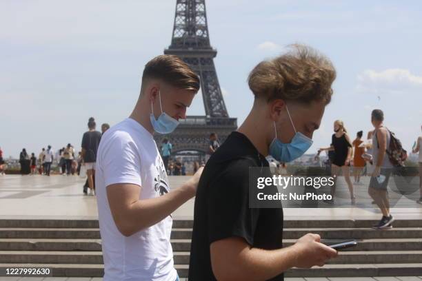 Tourists with a mask walking with a protective mask a front the Eiffel Tower during the first Summer hot day in Paris, France, on August 10, 2020.