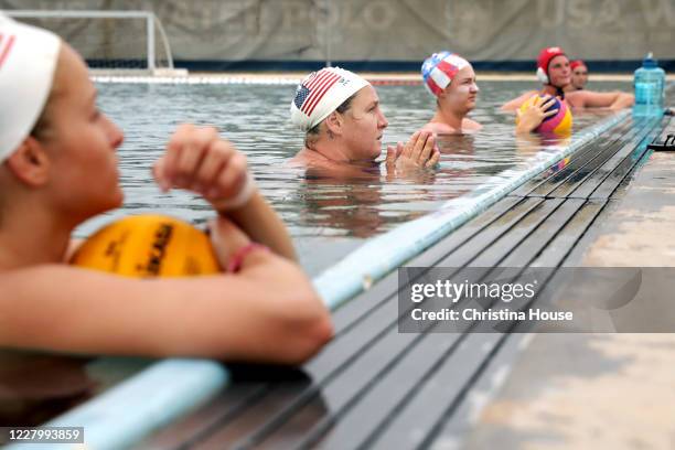 Women's water polo team members including Melissa Seidemann, second from left, listen to coach Adam Krikorian's instructions at Joint Forces Training...