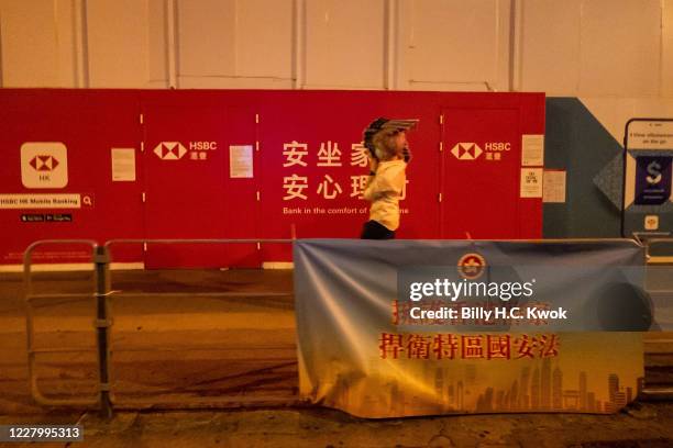 An employee of Jie Genge restaurant, walks past a security law banner when he buys bundles of Apple Daily newspaper for their clients, to show...