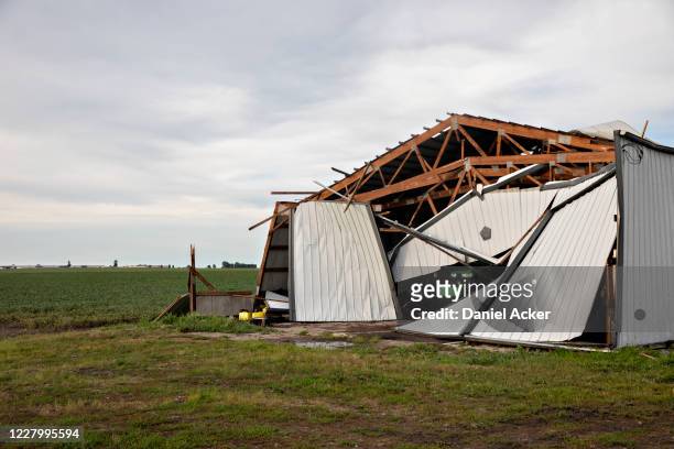John Deere agricultural tractor sits under a collapsed building following a derecho storm, a widespread wind storm associated with a band of rapidly...