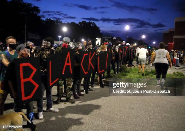 Protesters line up with series of wooden shields that spell out the " Black Lives Matter" on the parking lot of the Ferguson Police Department in...