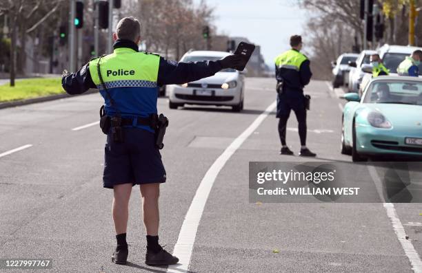 Police officers pull a car over for a licence and permit check in Melbourne on August 11 during a strict stage four lockdown of the city due to a...