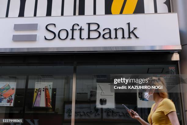 Woman walks past a SoftBank mobile store in Tokyo on August 11, 2020. - SoftBank Group on August 11 reported a 12 billion USD quarterly net profit to...