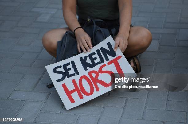 August 2020, Berlin: At the rally of the Seebrücke association "Seehofer Druck machen - Berlin muss klagen!" a demonstrator holds a poster with the...