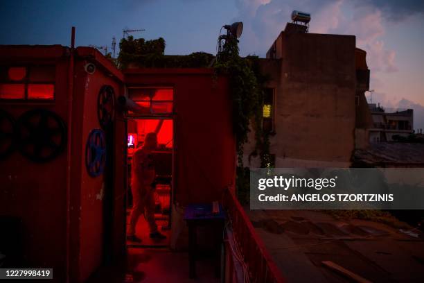 Projector operator of the open-air cinema "Zephyros" Pavlos Lepeniotis stands in the projection booth in Athens on August 1, 2020. - Real...