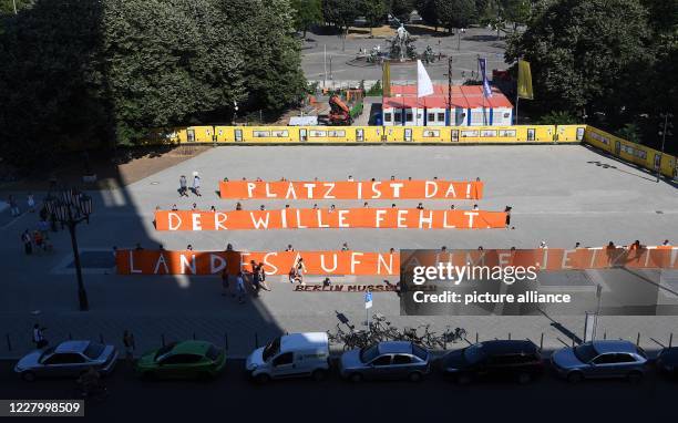 August 2020, Berlin: Demonstrators at the rally of the Seebrücke association "Seehofer Druck machen - Berlin muss klagen!" hold a poster with the...