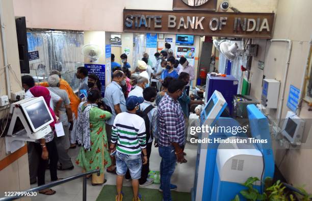 People crowd at the entrance of a State Bank of India branch while waiting to make transactions, at Laxmi Nagar, on August 10, 2020 in New Delhi,...