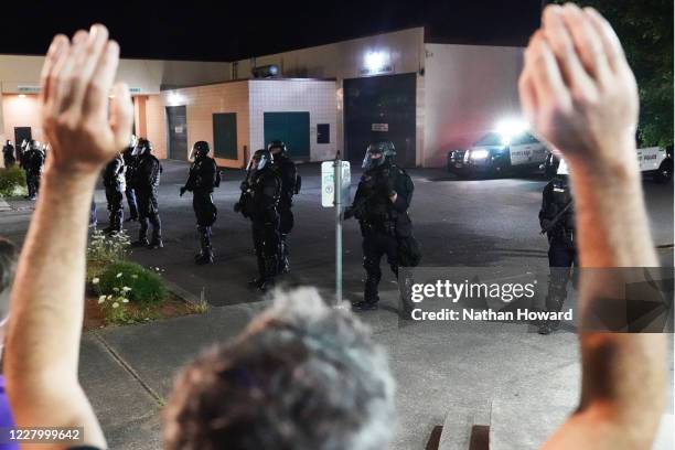 Protester hold his hands in the air while facing off with police near the Portland Police Bureau North Precinct on the 75th day of protests against...