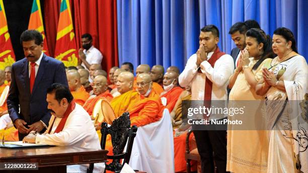 Sri Lankan prime minister Mahinda Rajapaksa signs the official papers to assume duties watched by his family members standing in the right corner of...