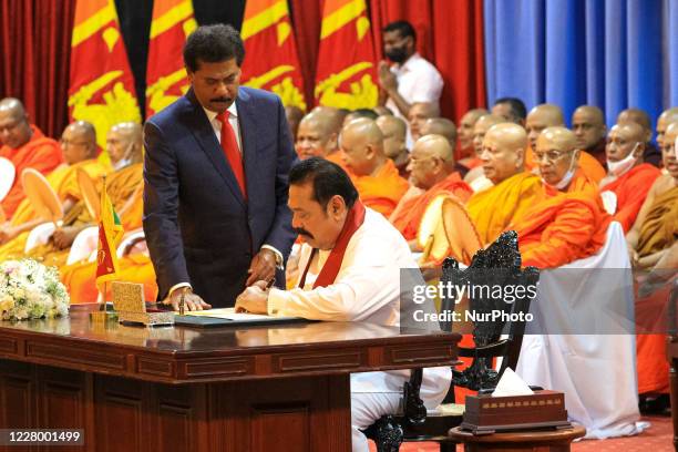 Sri Lankan prime minister Mahinda Rajapaksa signs the official papers to assume duties while the prime minister's secretary Gamini Senarath looks on...