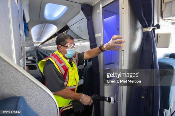 Cleaning supervisor Jose Mendoza uses an electrostatic sprayer to disinfect the bathroom inside a United Airlines 737 jet before passengers are...