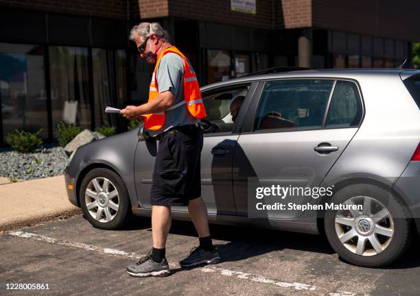 An election judge receives a ballot from a voter at a drive through drop-off for absentee ballots on August 11, 2020 in Minneapolis, Minnesota....