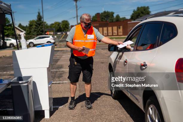 An election judge receives a ballot from a voter at a drive through drop-off for absentee ballots on August 11, 2020 in Minneapolis, Minnesota....