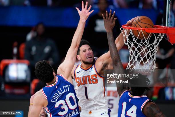 Devin Booker of the Phoenix Suns dunks the ball against Furkan Korkmaz and Norvel Pelle of the Philadelphia 76ers during the second half of an NBA...