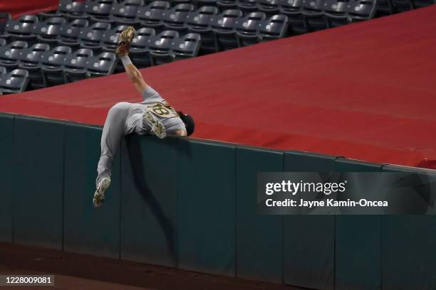 Chad Pinder of the Oakland Athletics reaches into foul territory and hangs on to the ball hit by Mike Trout of the Los Angeles Angels for the third...