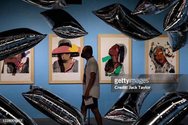 Visitor walks past 10 screen prints entitled 'Ladies and Gentlemen' by Andy Warhol at the 'Andy Warhol: Pop Art' exhibition at the RCB Galleria on...