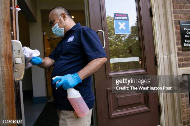 Ko Soe, a member of the university custodial staff, dis-infects a door handle at a classroom building on the University of North Carolina campus in...