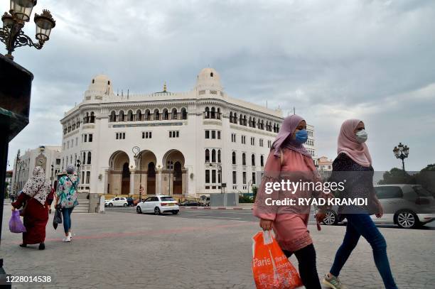 Algerian women wearing protective masks walk past the La Grande Poste building in the centre of the capital Algiers, on August 12, 2020.