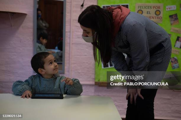 Teacher listens to a pre-school boy working in his "Ceibalita tablet" during a class in a public school in Montevideo, amid the COVID-19 novel...