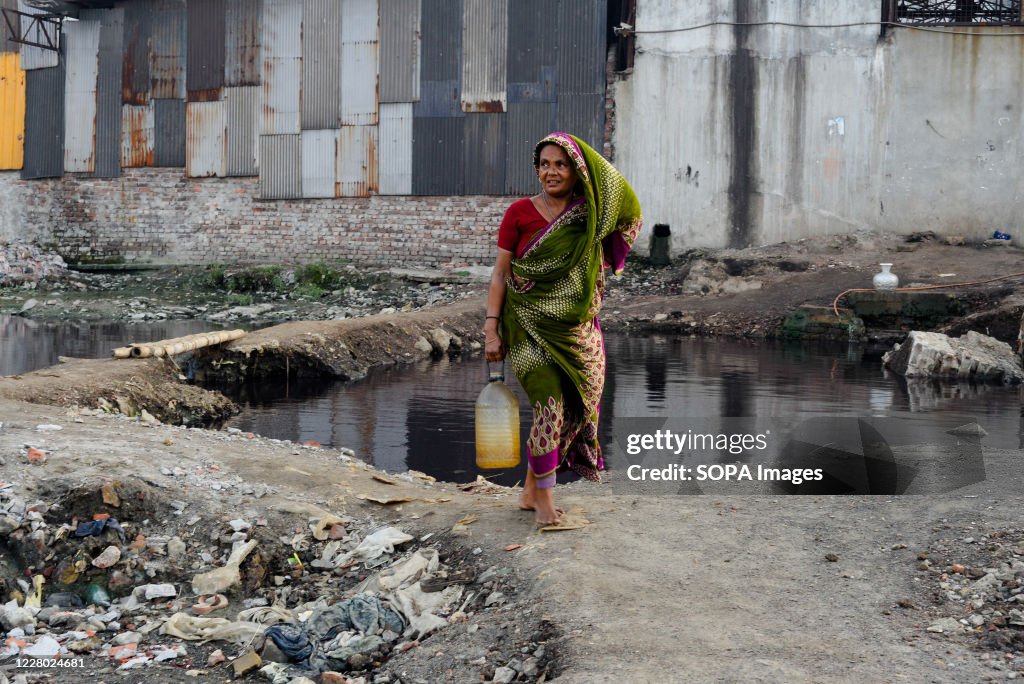 A woman collecting drinking water in an industrial area.