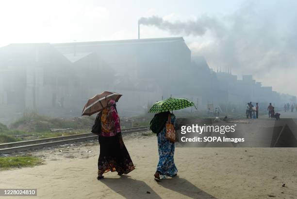 Women passing by an industrial area where air pollution is flagrant.Dhaka is going back to its normal life after some months of the ongoing pandemic.