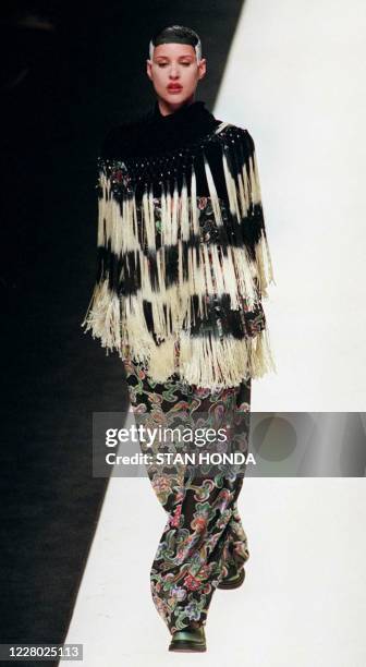 Model wears a black and white fringe wrap over a black top and multi-colored print trousers during the Giorgio Armani Fall-Winter fashion show 03...