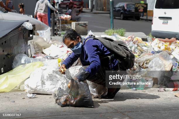 August 2020, Venezuela, Caracas: A woman is looking for food in the trash. In total, almost 30 000 people in Venezuela have become infected with the...