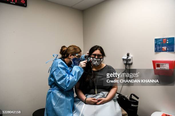 Doctor Nelia Sanchez-Crespo examines Heather Lieberman as she participates in a COVID-19 vaccination study at the Research Centers of America in...