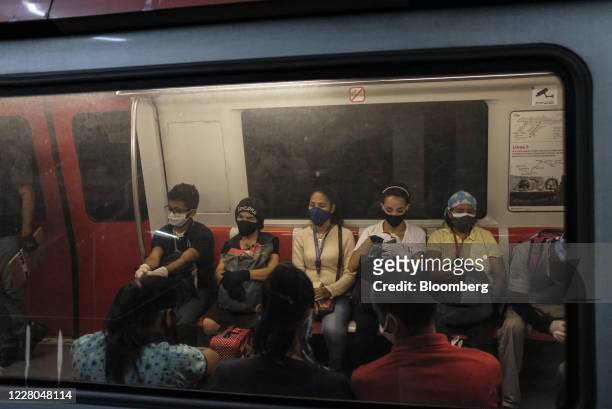 Commuters wearing protective masks ride a train at Colegio de Ingenieros subway station in Caracas, Venezuela, on Friday, Aug. 14, 2020. Venezuela is...