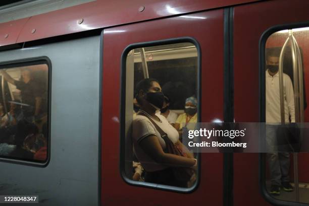 Commuters wearing protective masks ride inside a train at Colegio de Ingenieros subway station in Caracas, Venezuela, on Friday, Aug. 14, 2020....
