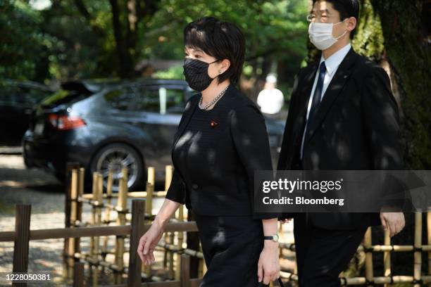 Sanae Takaichi, Japan's internal affairs minister, wearing a protective mask, left, arrives at the Yasukuni Shrine on the anniversary of the end of...